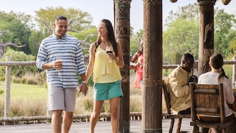5 people drink wine near a gazebo and a forest