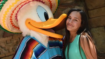 A young female Guest enjoys an affectionate greeting with Donald Duck at the Mexico Pavilion at Epcot