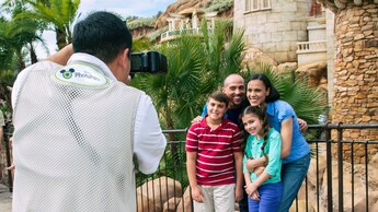 Una familia posa frente a un castillo mientras un fotógrafo de Disney PhotoPass toma una foto