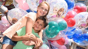 Une fille enroule ses bras autour de son petit frère devant une foule de ballons