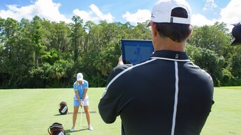 Un instructor de golf filma a un Huésped durante una sesión de entrenamiento profesional en Walt Disney World Resort