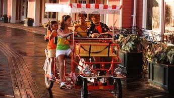Family of 4 in a fringe-canopied quad-cycle pedal car