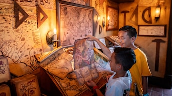 Two young Guests reading a treasure map in The Crow’s Nest at Magic Kingdom park