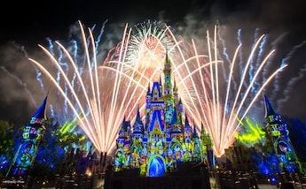 Fireworks burst over Cinderella Castle as lights cover it in a stained glass theme