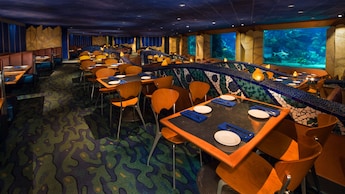 The dining area in Coral Reef Restaurant, which features panoramic windows with views into a giant aquarium