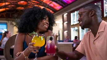 2 Visitantes levantan sus copas en un brindis mientras cenan en Toledo en Disney’s Coronado Springs Resort
