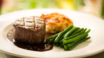 Grilled tenderloin of beef on a plate with green beans and gratin dauphinois potatoes