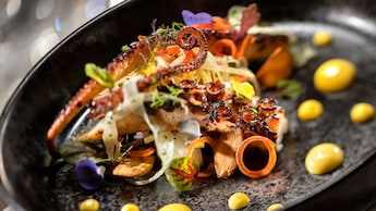 Grilled octopus in a pan surrounded by leafy garnishes