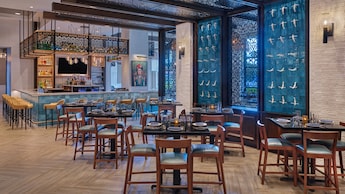 Un restaurante bar y área de comidas con decoración moderna y un mural con arte mexicano
