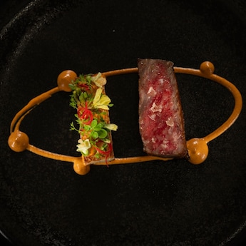 An elegant dish featuring a slice of Wagyu beef and a romesco rosti