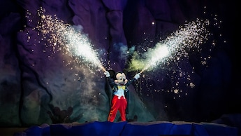 Fuegos artificiales se disparan de las manos de Mickey Mouse mientras está en el escenario de Fantasmic