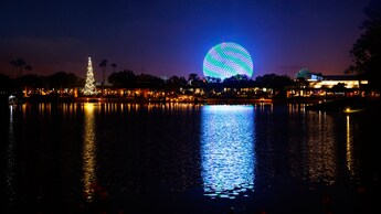 A Christmas tree and Spaceship Earth lit up at night