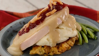 Pavo servido con puré de papas, relleno y salsa de arándanos rojos