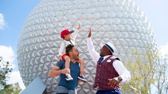Um menino sentado nos ombros de seu pai e cumprimentando um Guia VIP Tour no EPCOT