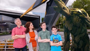A family of 4 poses for a photo in front of Guardians of the Galaxy Cosmic Rewind with an image of Groot