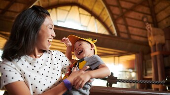 A smiling woman holding a laughing child inside Disney’s Animal Kingdom Lodge