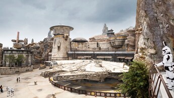 Millennium Falcon docked in Star Wars, Galaxy’s Edge with a stormtrooper standing on a balcony nearby