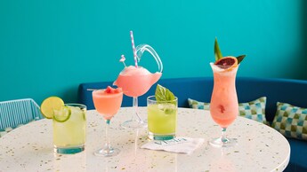 A table set with 5 different drinks next to a wall with a sign that reads "Vista Parkside Market"