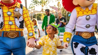 A boy holds hands with the characters Woody and Jessie from the Disney and Pixar film Toy Story 2