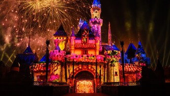 Sleeping Beauty Castle illuminated at night with lighting and fireworks