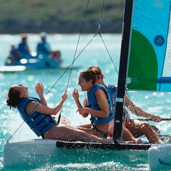2 teenage girls in life vests laugh while sailing on a small boat 2 teenage girls in life vests laugh while sailing on a small boat