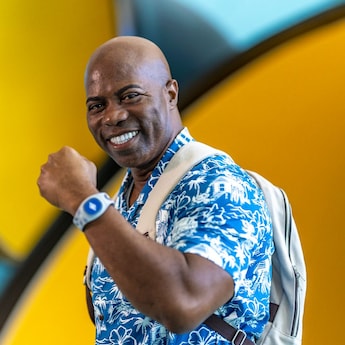 A man smiles while raising his arm up to show off his Disney Band Plus A man smiles while raising his arm up to show off his Disney Band Plus