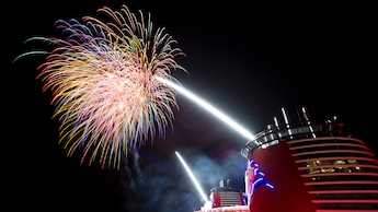 Brilliant fireworks light up the night sky above a Disney Cruise Line ship