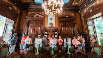 People take photos and look at artwork while walking through a historic room