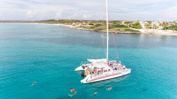 Personas nadando en el océano en un catamarán con pasajeros cerca de la costa