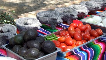 Vegetales frescos en recipientes de metal frente a tazones de piedra con forma de cerdo