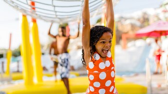 A young girl in a swimsuit smiles in a water park