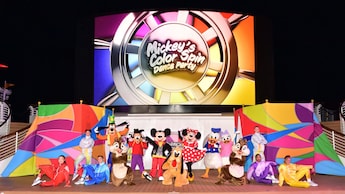 A scene from Mickey’s Color Spin Dance Party featuring Disney Characters and Cast Members posing for a picture on the Funnel Vision Deck Stage of a Disney Cruise Line ship