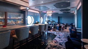 The interior of Nightingale’s reveals an elegant piano lounge with a bar, cushioned seating and port hole windows