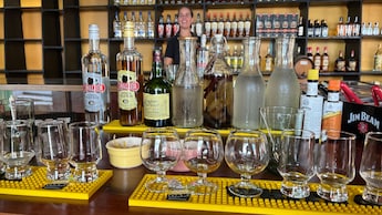 A table with different rum bottles, glasses and cocktail making equipment at a traditional rum shop in Saint John’s