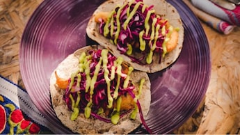 Dos tacos de pescado cubiertos con repollo rallado y salsa de aguacate