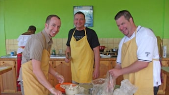 Three men preparing a meal in a kitchen in Roseau, Dominica