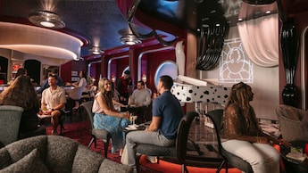 Guests socializing in De Vil's, an elegant 101 Dalmatians themed piano lounge aboard the Disney Destiny
