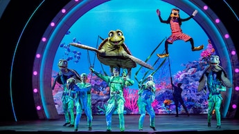Goofy and Crush with a group of performers on stage during a number from Disney Seas the Adventure
