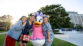 Three Guests posing with Daisy Duck in front of Disney’s Contemporary Resort