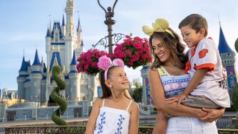Una madre con 2 niños pequeños de pie cerca de Cinderella Castle en Magic Kingdom Park