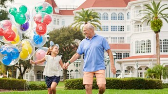 Un niño sostiene globos de Mickey Mouse mientras camina con un adulto en Disney’s Grand Floridian Resort & Spa