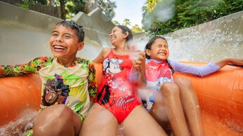 Three Guests getting splashed on an inflatable raft riding an attraction at Disney's Typhoon Lagoon Water Park