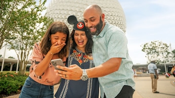A family laughing as they view a photo on their phone