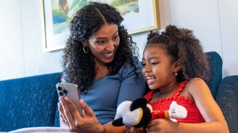 A mom holding her phone up for her daughter