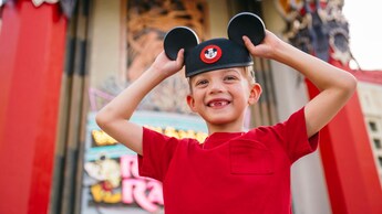 A smiling boy wearing a Mickey Mouse ear hat while standing in front of Grauman's Chinese Theatre.