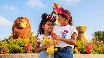 Two young Guests with Minnie Mouse ear headbands hugging in front of The Lion King topiaries at Epcot Flower & Garden Festival