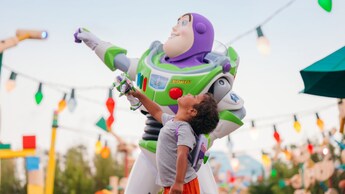 A boy standing next to Buzz Lightyear in Toy Story Land