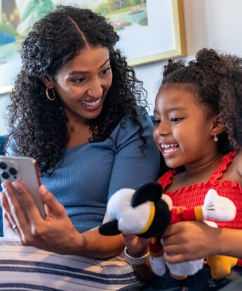 A mom holding her phone up for her daughter