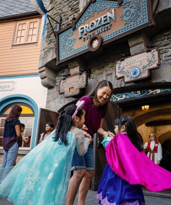 Two girls running to their mother in front of Frozen Ever After in Epcot