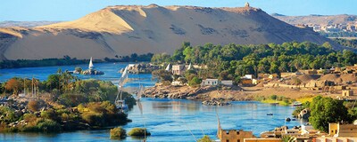A waterway flows through a seaside village and mountainous desert region